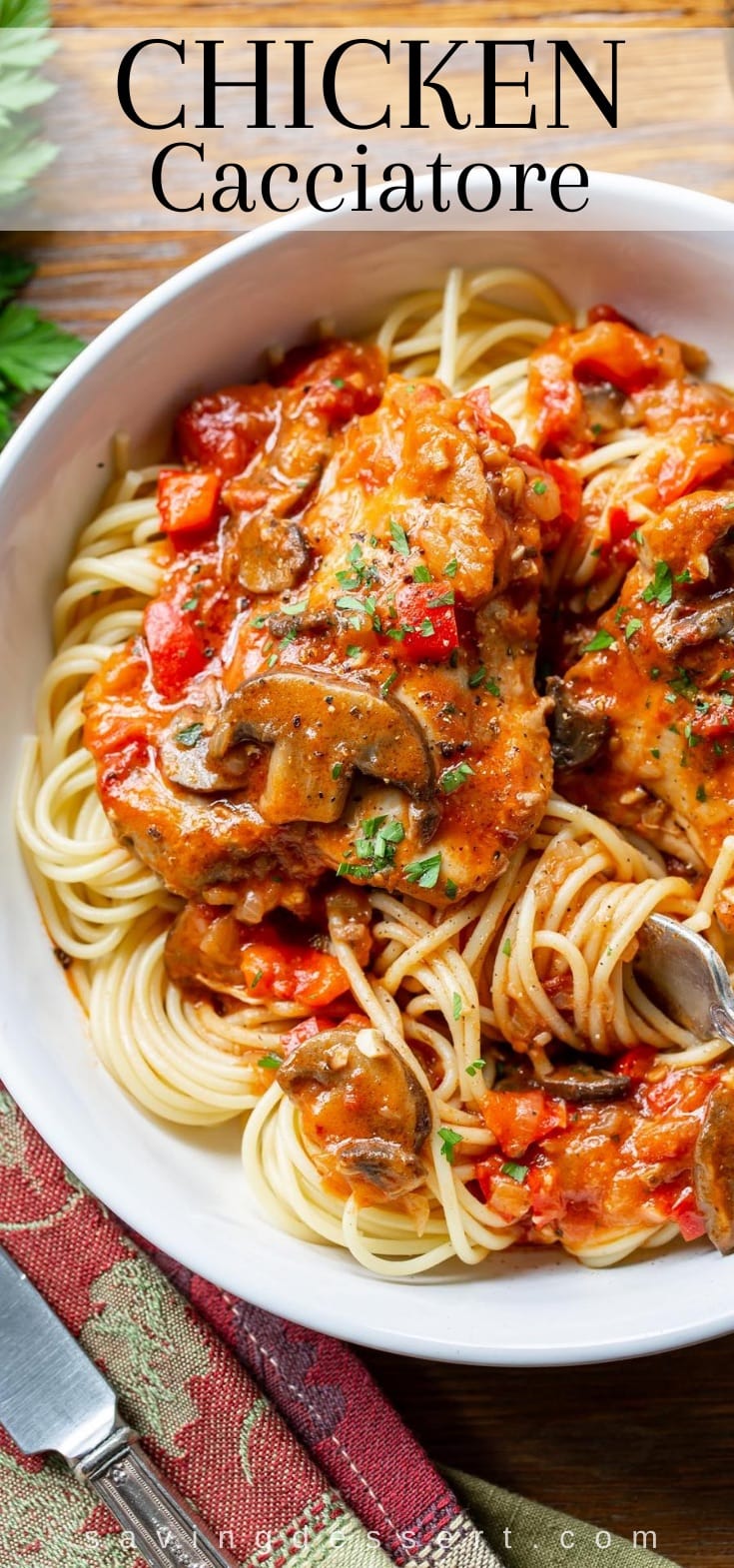 A bowl of spaghetti topped with chicken cacciatore and fresh parsley