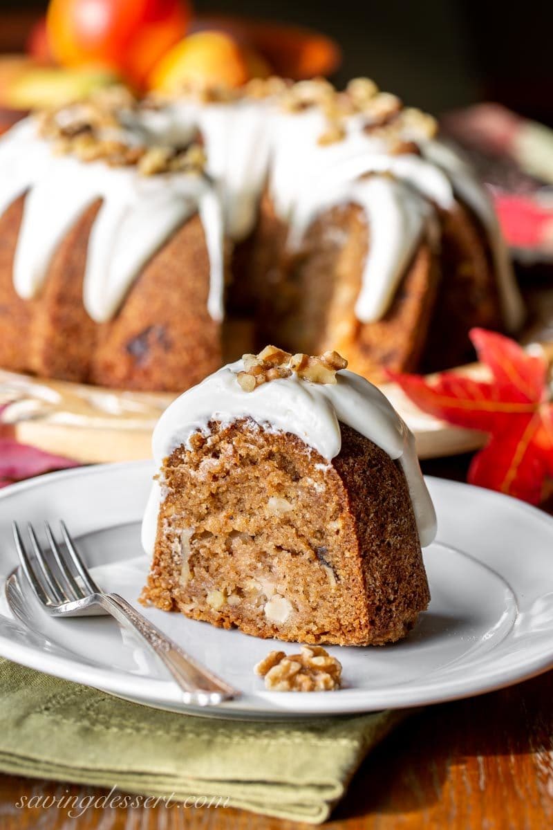 A slice of fresh apple bundt cake with cream cheese icing and walnuts
