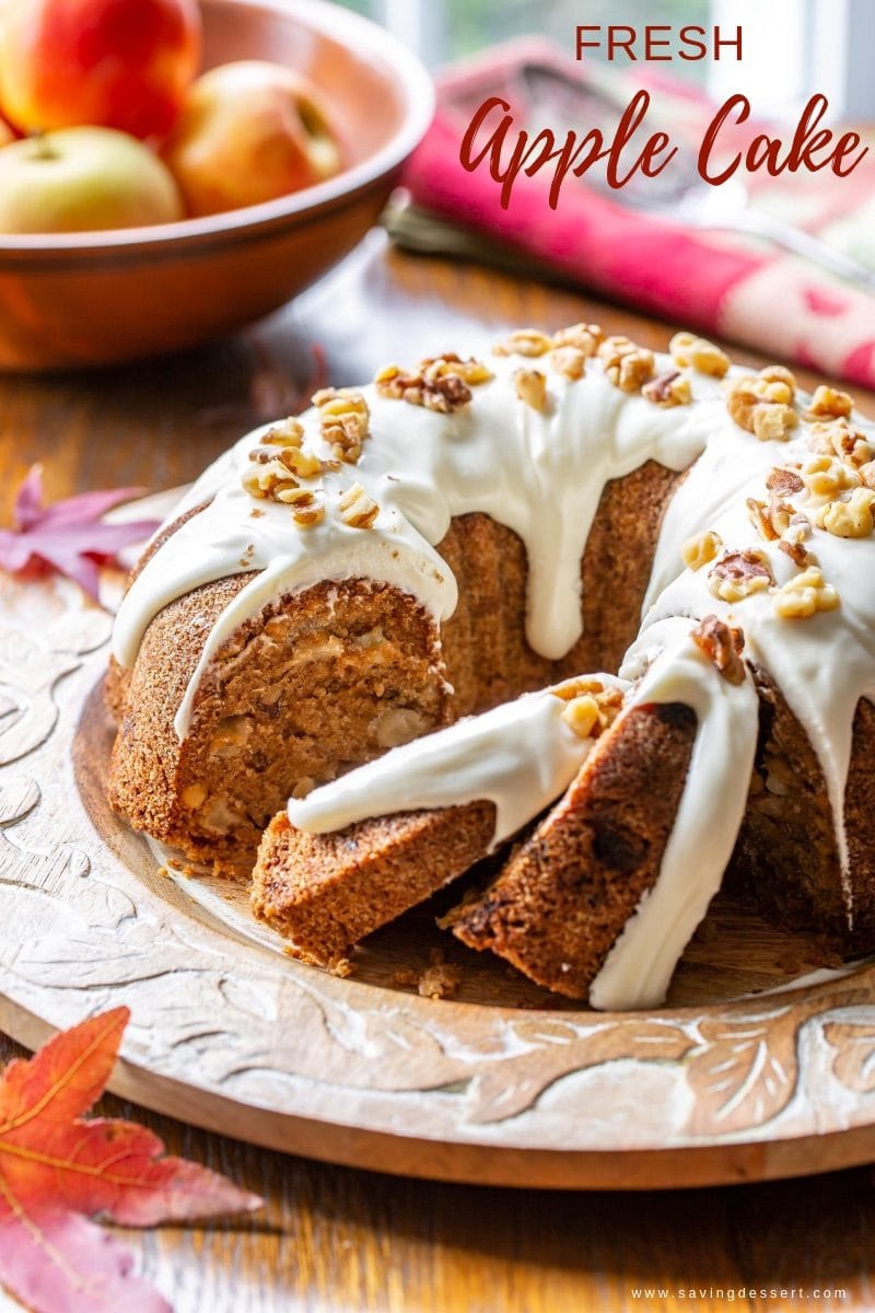 A sliced fresh apple Bundt cake with cream cheese icing and chopped walnuts