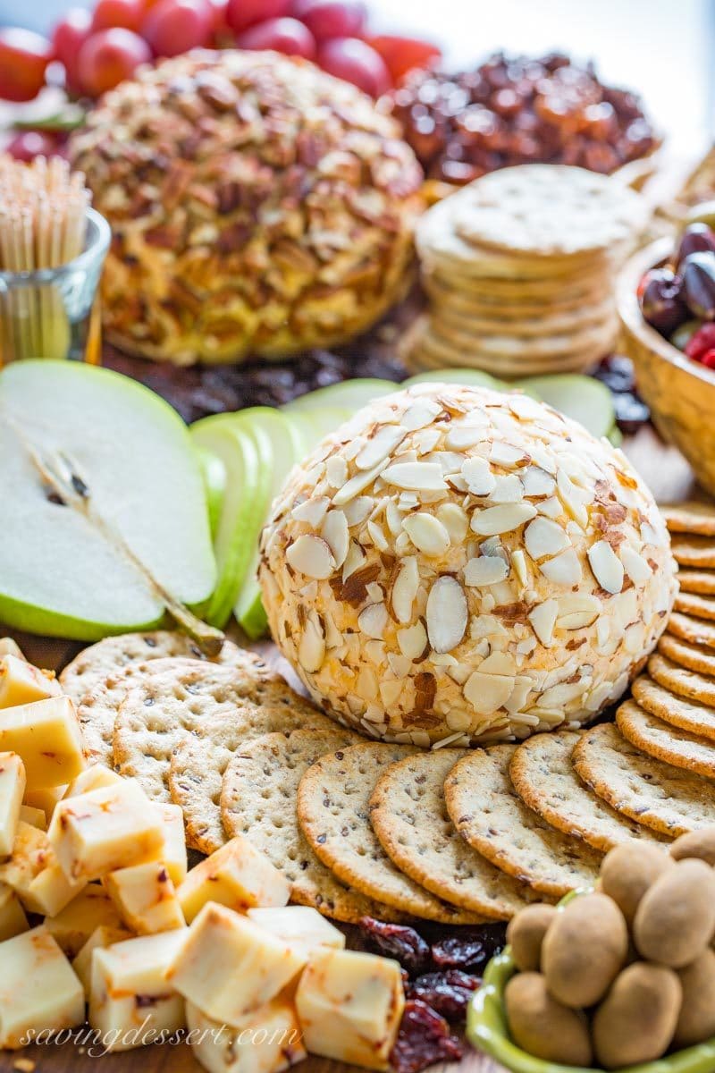 A large platter with a cheeseball, crackers, fruit, nuts and olives.