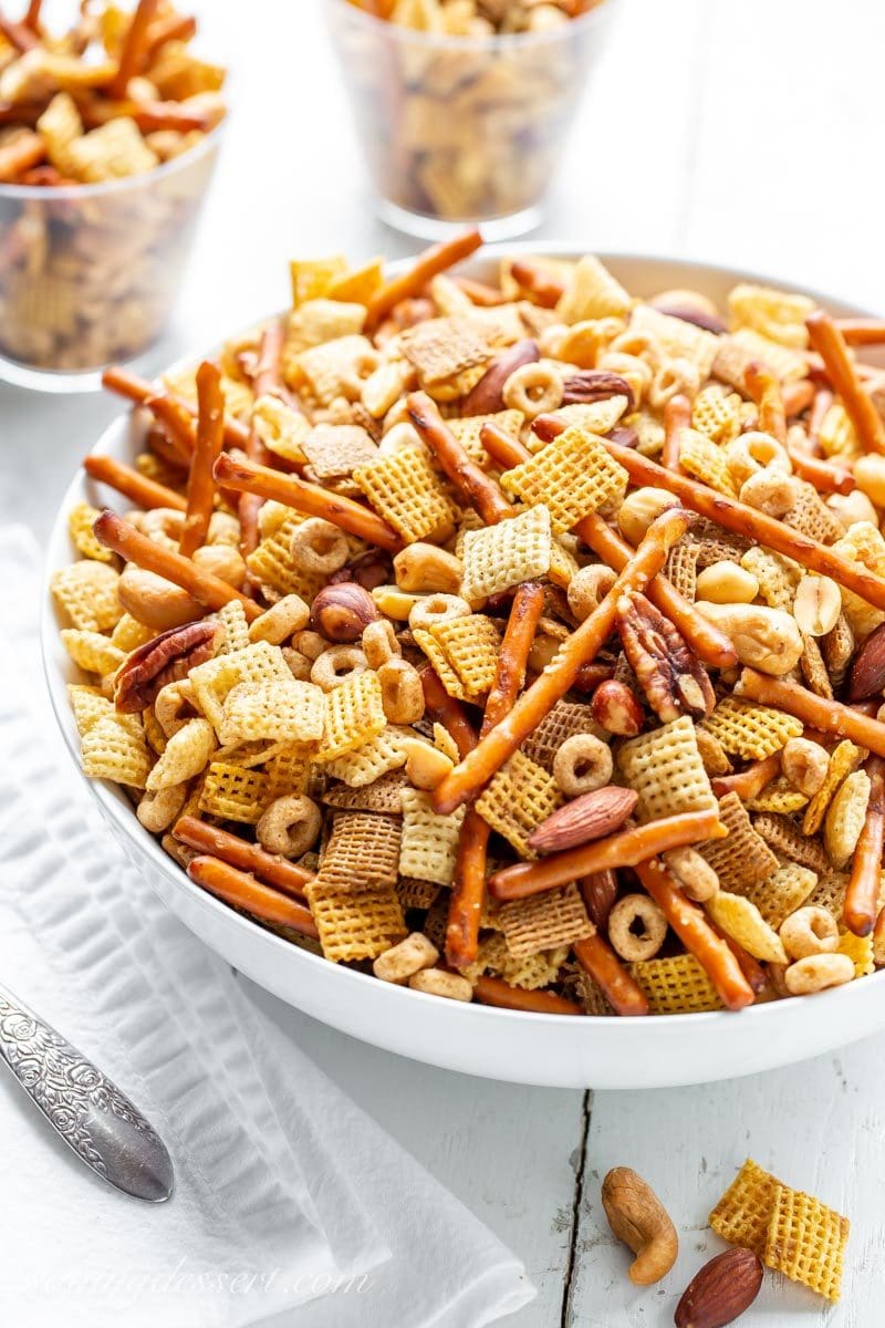 A big bowl of Party Chex Mix with Chex cereal, pretzel sticks, assorted nuts and Cheerios