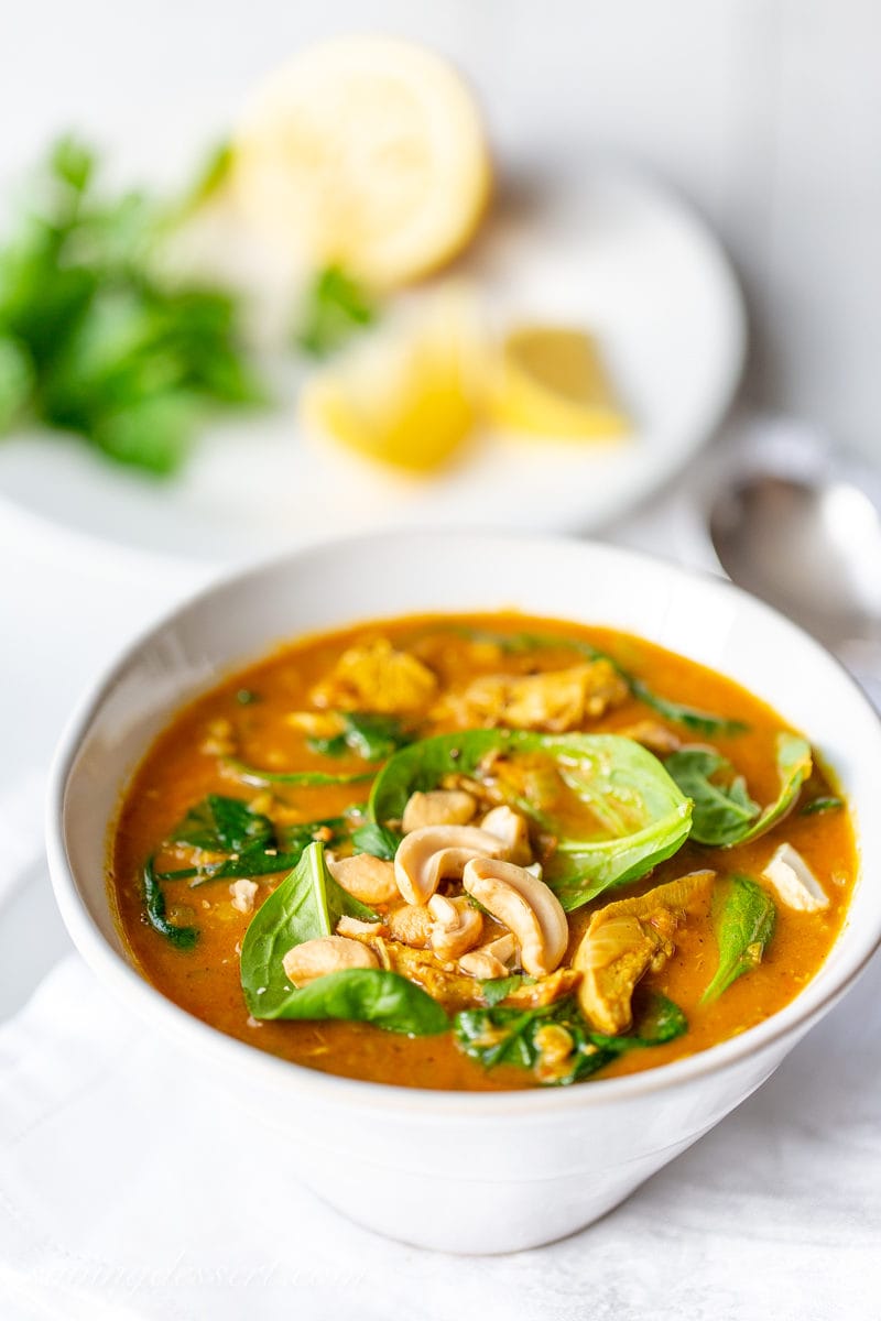 A bowl of creamy coconut chicken soup with spinach, lentils, lemon and cashews