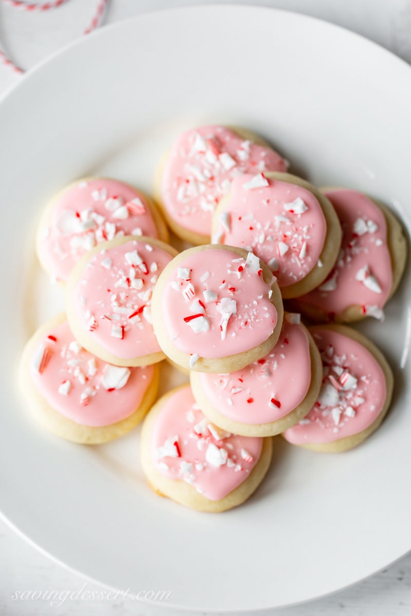 A plate of Peppermint Meltaway Cookies with pink icing and crushed peppermint candy on top