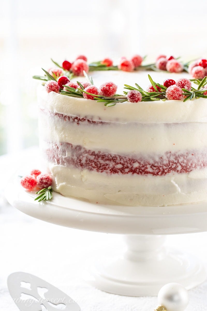 Red Velvet Layer Cake with Rosemary and sugared cranberries on top forming a wreath