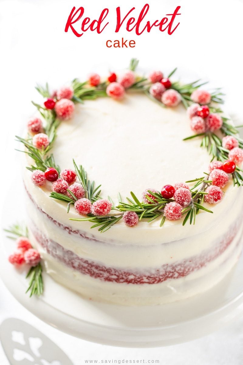 Red Velvet Layer Cake with a wreath on top made of sugared cranberries and rosemary sprigs