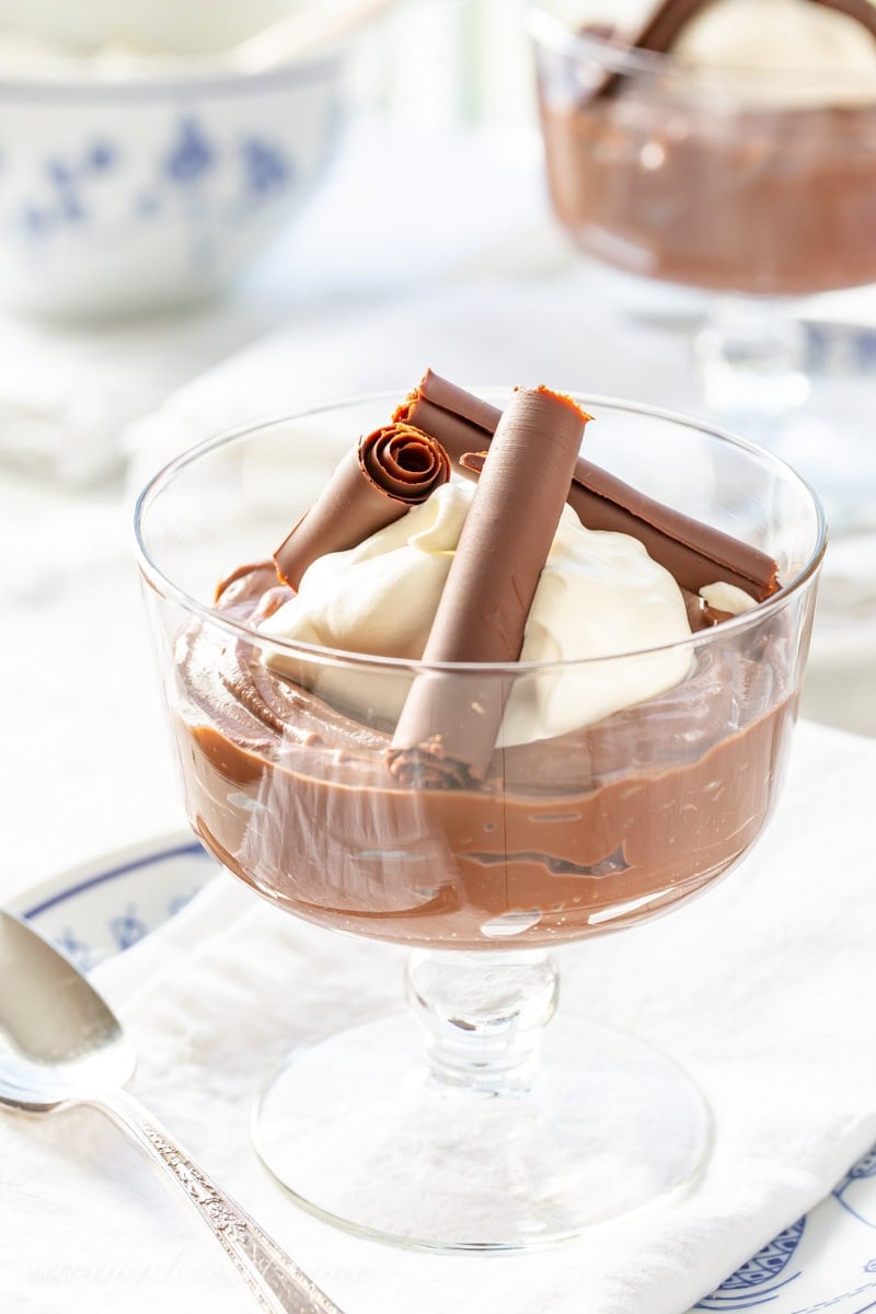 A bowl of rich chocolate pudding topped with whipped cream and chocolate curls
