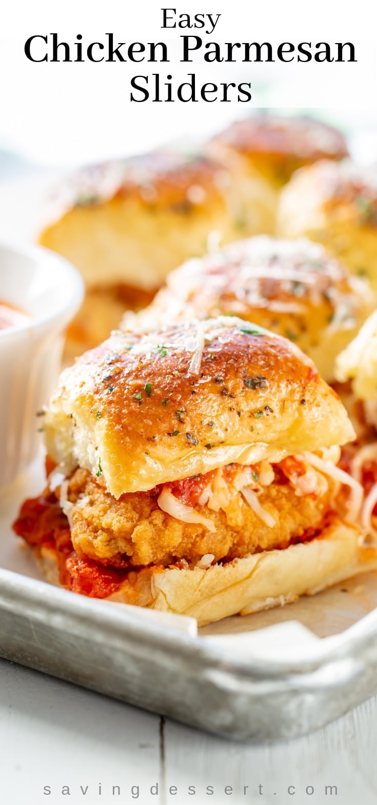 A pan loaded with chicken parmesan sliders with cheese and pizza sauce