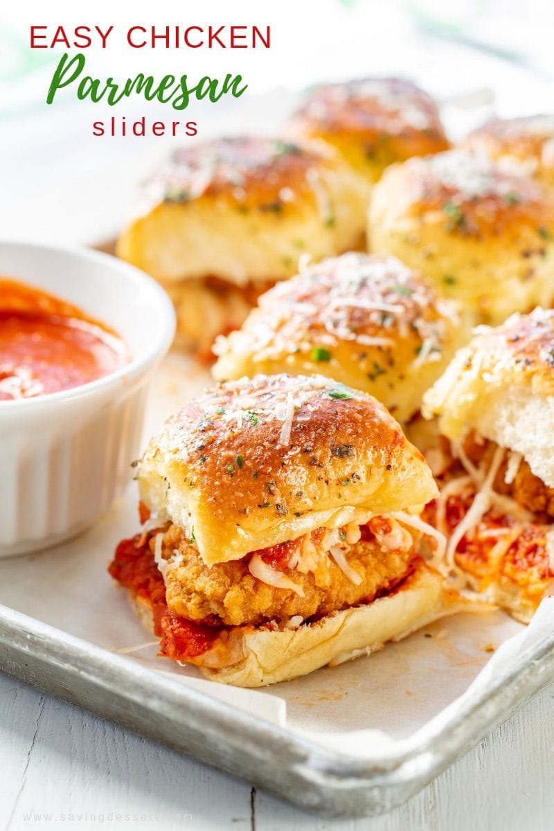A tray with Chicken Parmesan Sliders with extra pizza sauce on the side. 