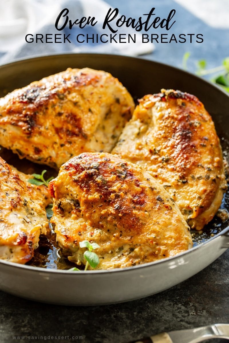 A pan of oven roasted Greek Chicken Breasts with fresh herbs and garlic