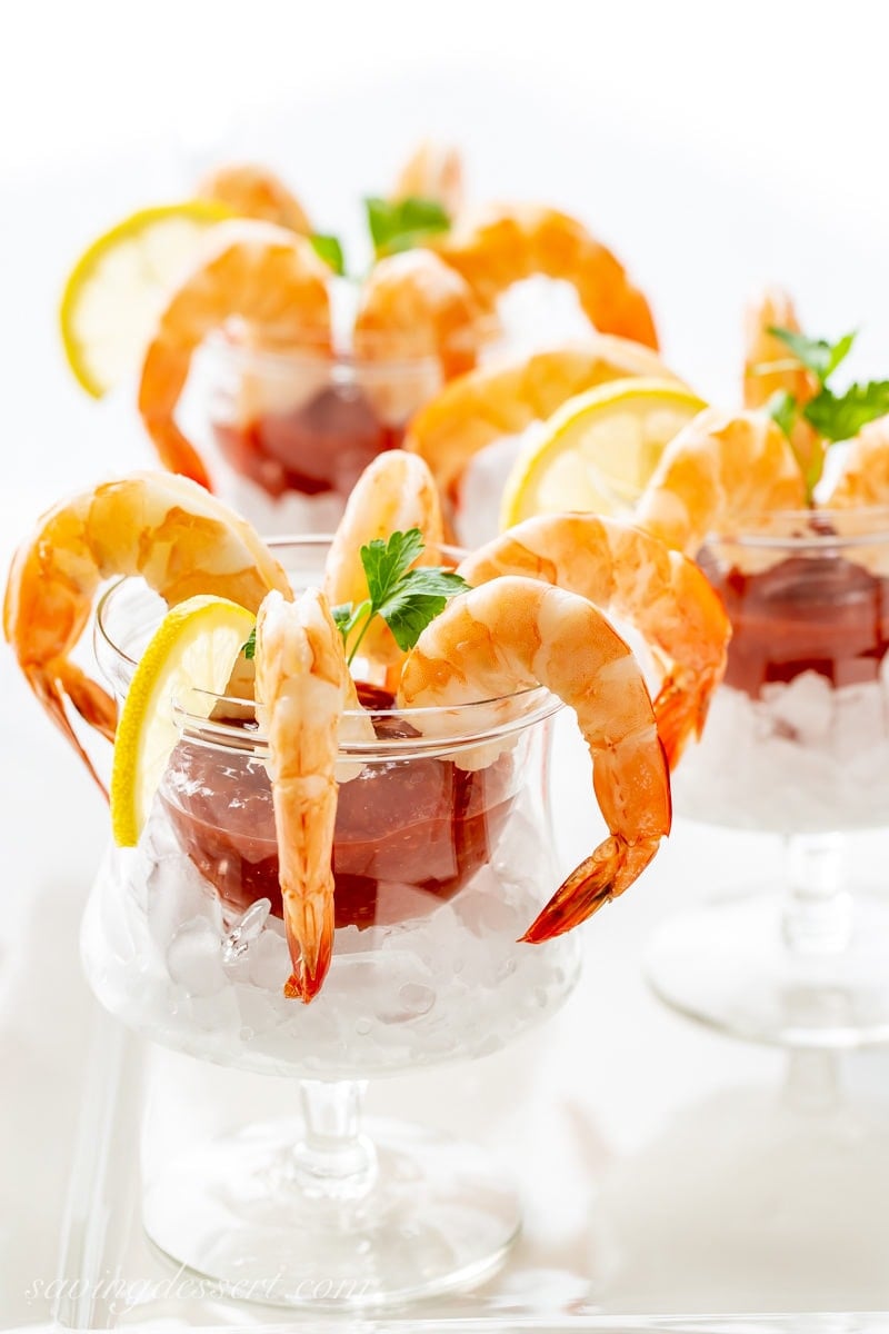 Individual glasses of shrimp cocktail with cocktail sauce and lemon slices