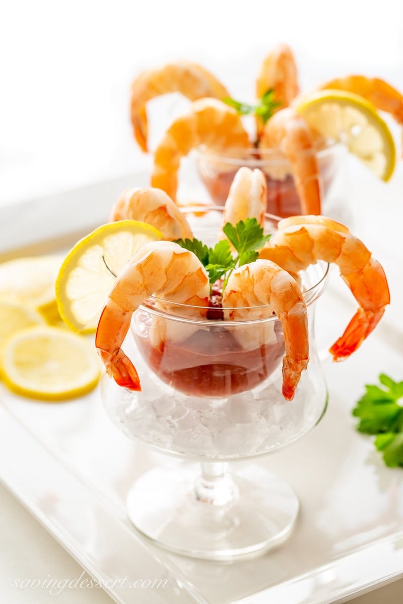 Glasses of shrimp cocktail with slices of lemon, parsley and cocktail sauce