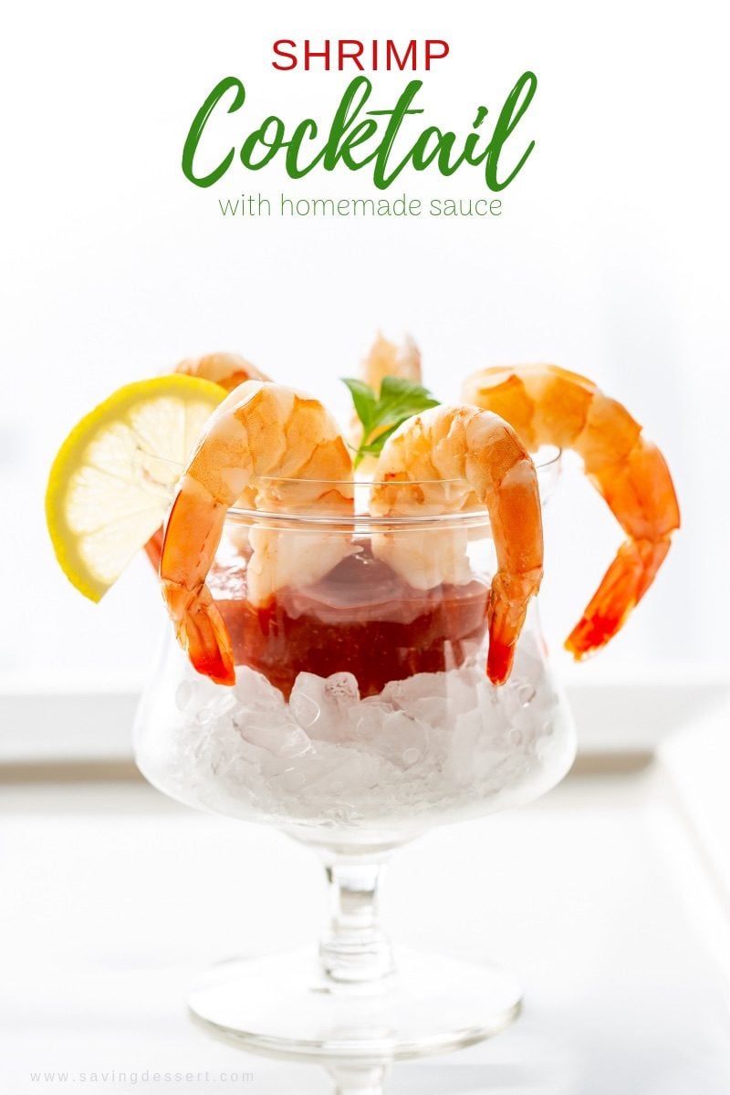 A glass of shrimp cocktail with cocktail sauce, lemon and parsley