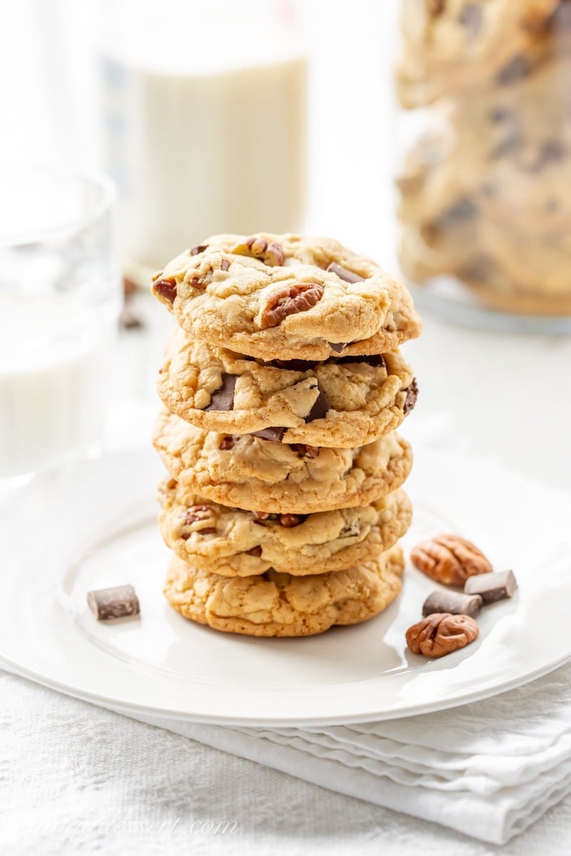 A stack of chocolate chunk cookies with pecans and a bottle of milk