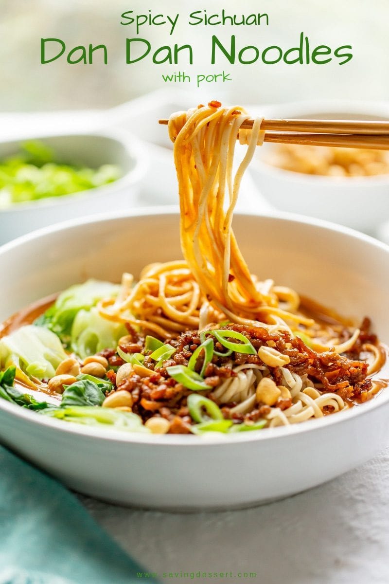 A bowl of spicy Dan Dan Noodles with a peanut sauce, bok choy, minced pork and sliced green onions.