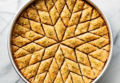 A large round baking pan filled with honey baklava cut into diamond wedges