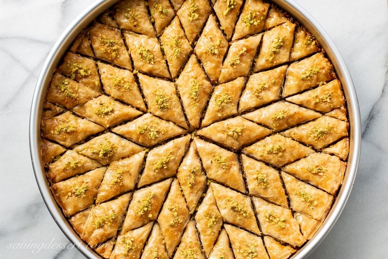 A large round baking pan filled with honey baklava cut into diamond wedges