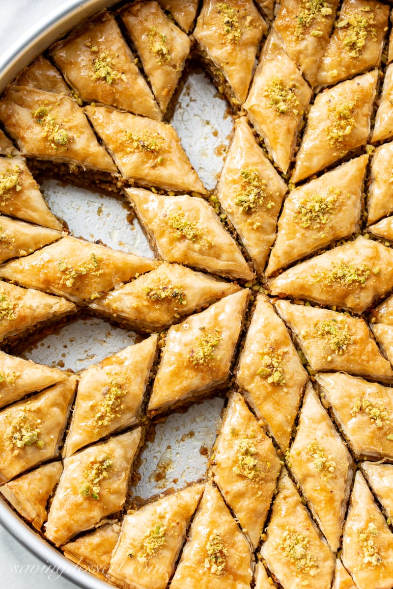 A pan of sliced honey baklava sprinkled with chopped pistachios
