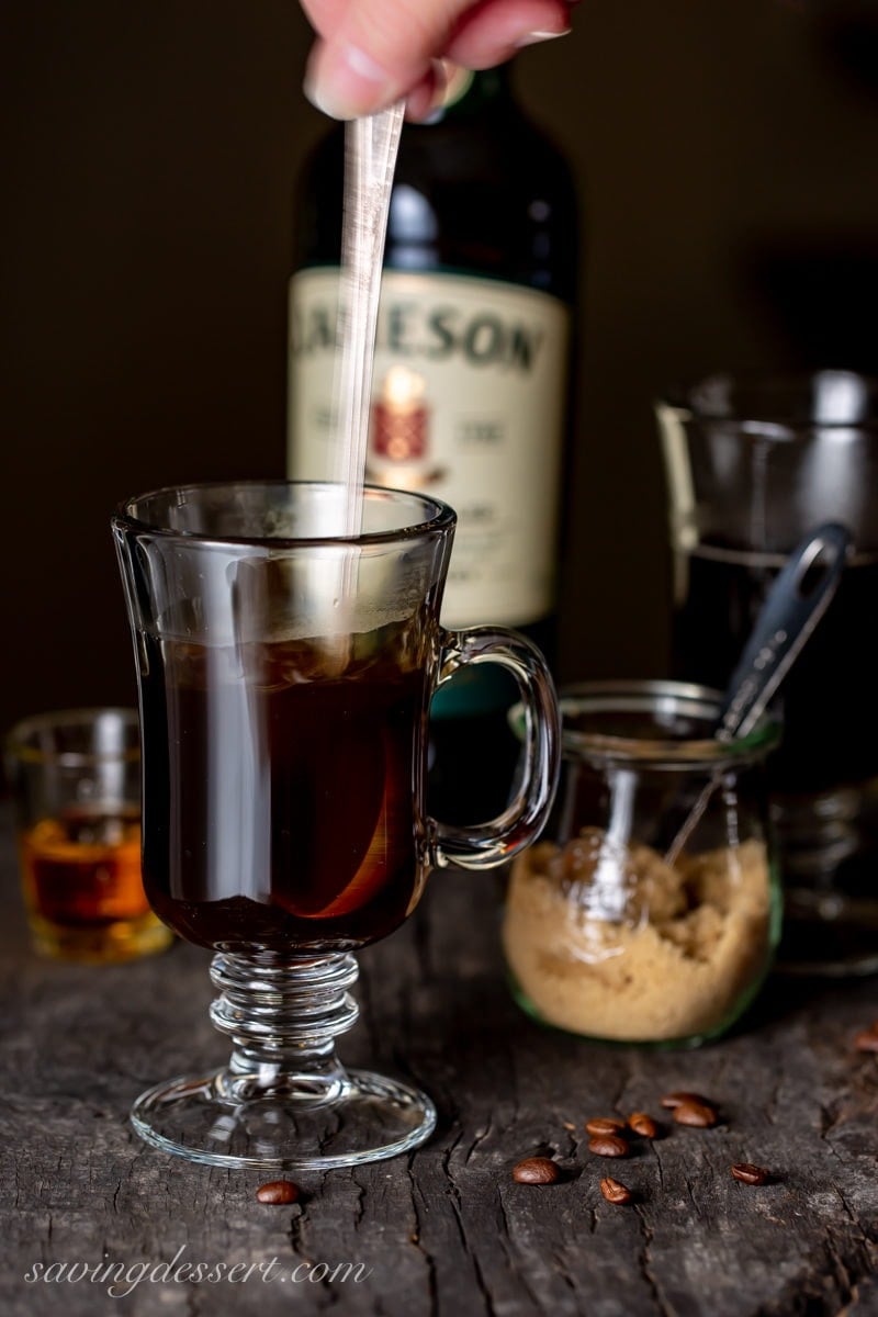 Stirring hot coffee in a clear mug as part of an Irish Coffee recipe