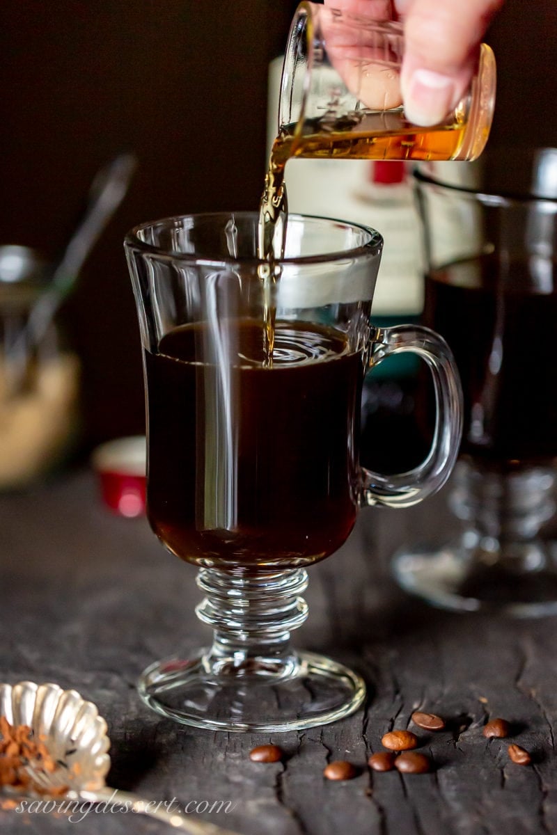 Pouring Irish whiskey into a clear mug with coffee