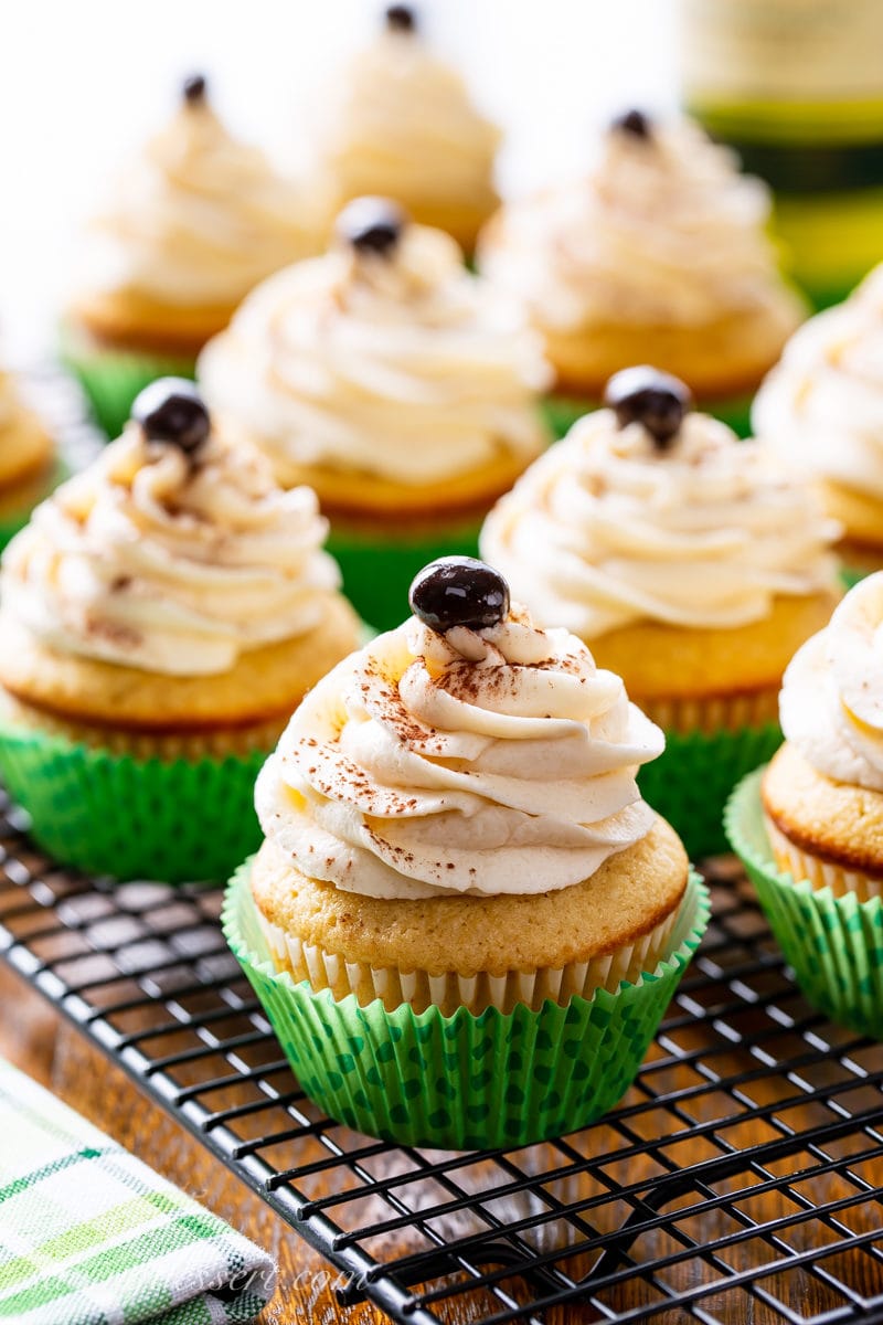 A closeup of Irish Coffee Cupcakes in a green liner with swirled frosting and a chocolate covered espresso bean on top