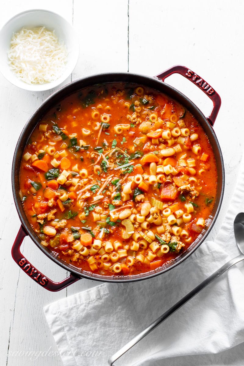 A large pot of Pasta e Fagioli soup with parsley, beans, pasta, vegetables and Italian sausage