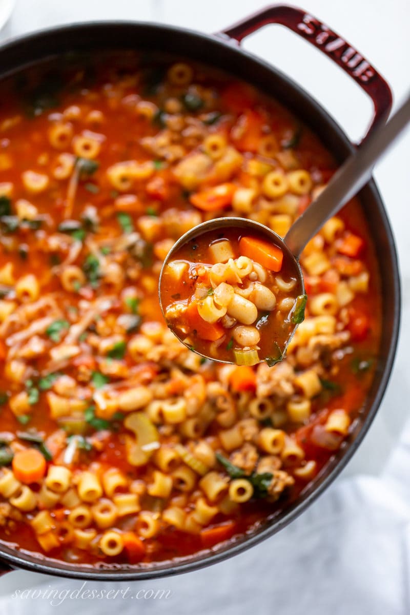 A ladle full of Pasta e Fagioli soup with beans, pasta, vegetables and Italian sausage