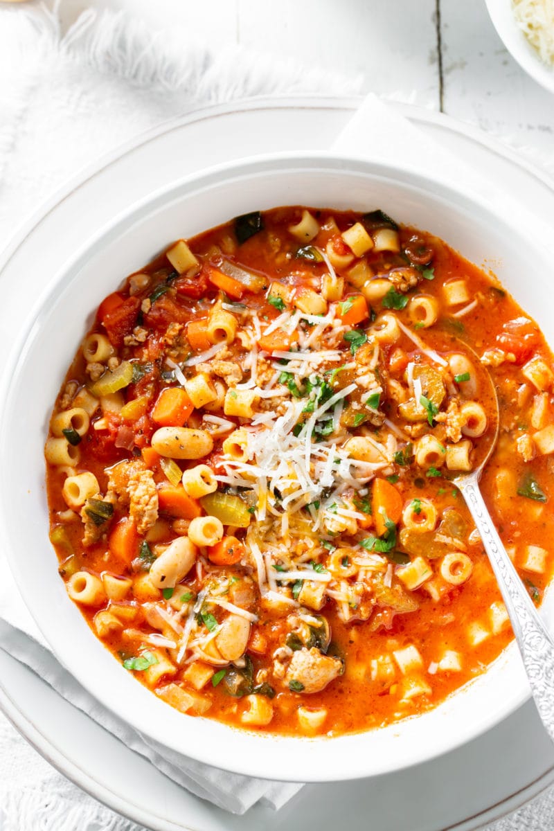 A big bowl of Pasta e Fagioli Soup with white beans and Italian sausage garnished with Parmesan and parsley