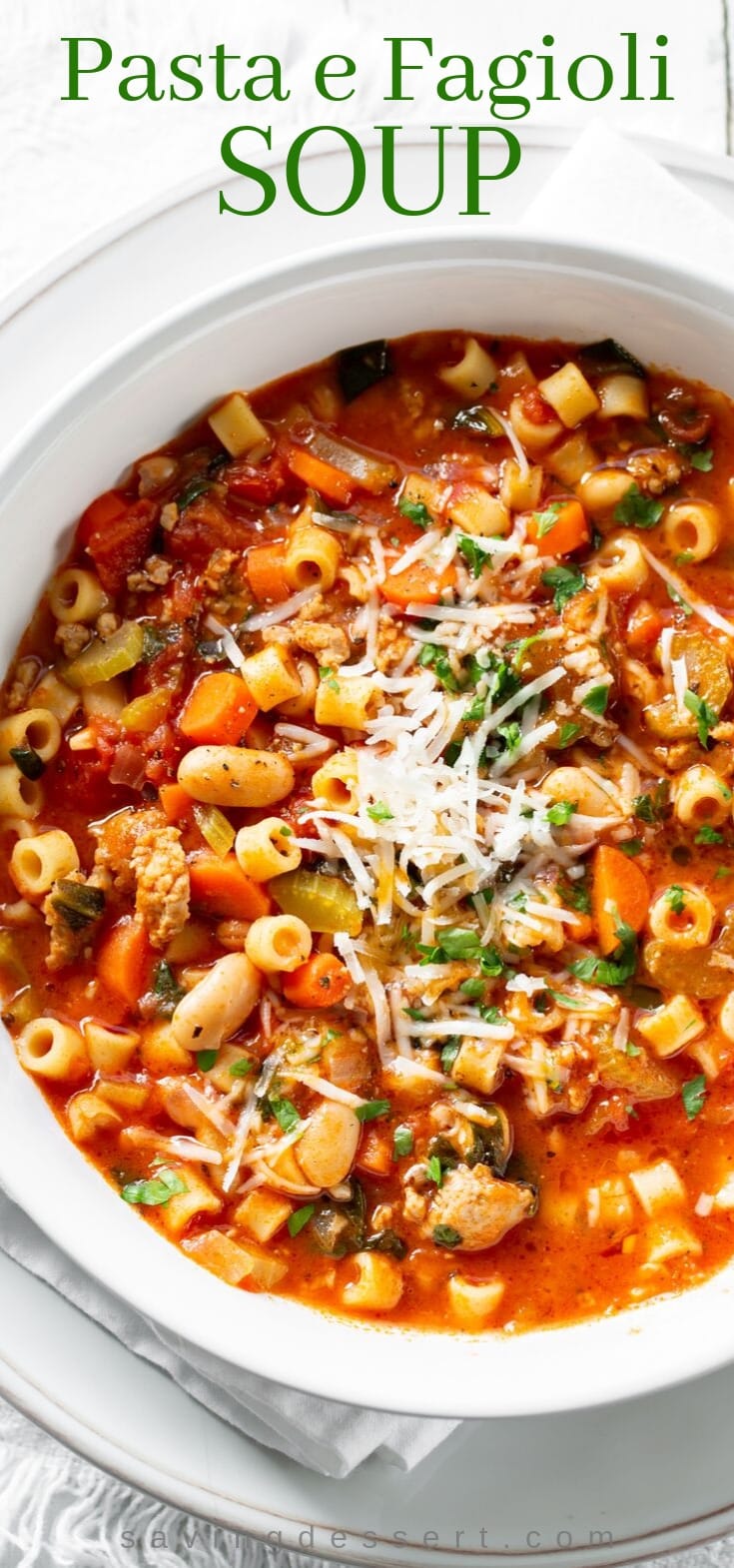 A big bowl of Pasta e Fagioli soup with Italian sausage and beans garnished with parsley and Parmesan