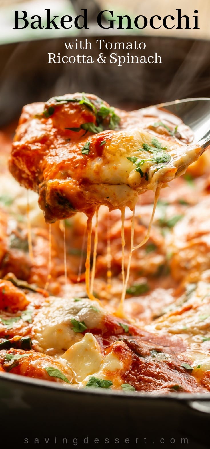 A spoonful of cheesy baked gnocchi with spinach and tomato sauce