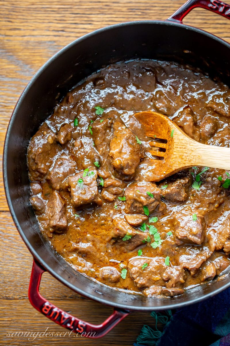 A Dutch oven pot with tender beef tips in a rich gravy with mushroom and onions