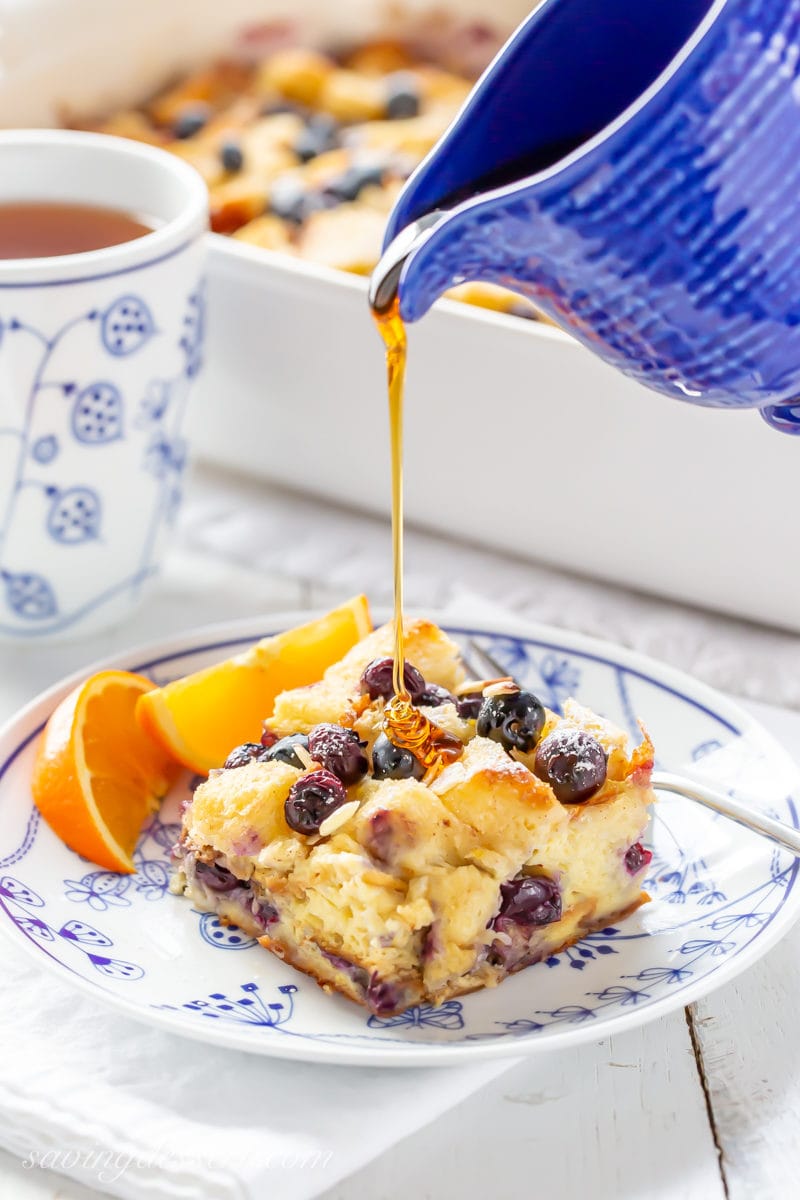 A piece of Blueberry Overnight French Toast Casserole being drizzled with maple syrup