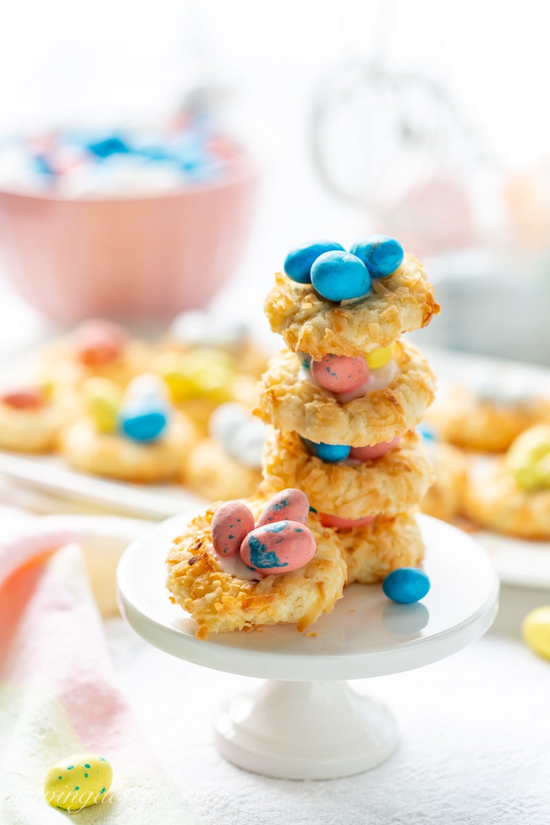 A stack of coconut thumbprint cookies with speckled eggs in the center