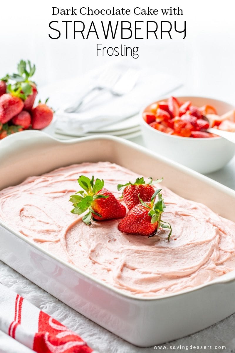 A dark chocolate sheet cake with fresh strawberry frosting garnished with fresh strawberries.