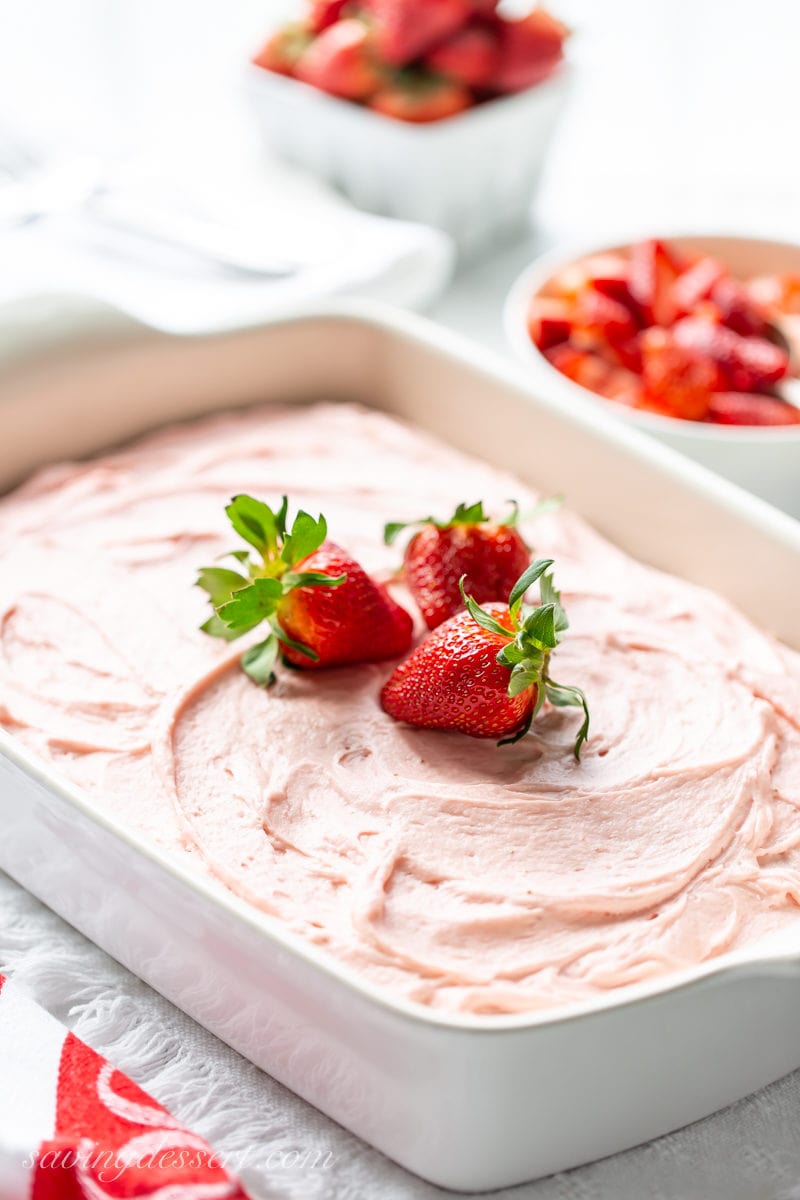 A sheet pan with dark chocolate cake topped with swirls of fresh strawberry frosting.