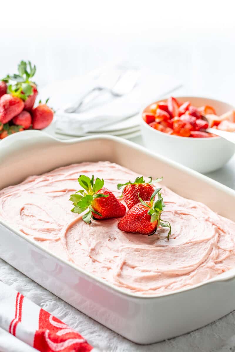A pan with chocolate cake and strawberry frosting with fresh berries on top