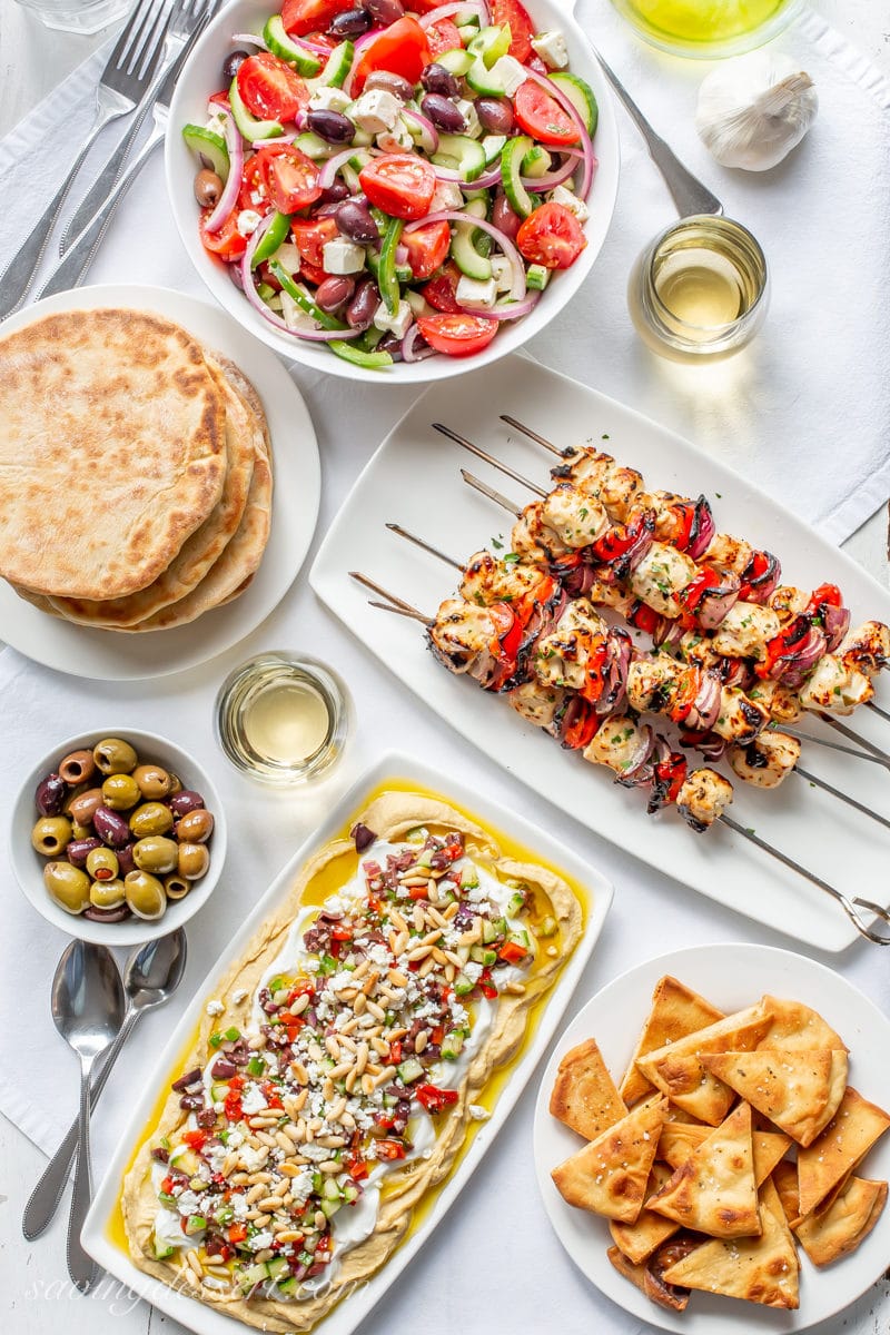 Grilled Greek Chicken Kabobs, Greek Salad, Greek Layered Hummus Dip, Whole Wheat Pita breads, wine and olives