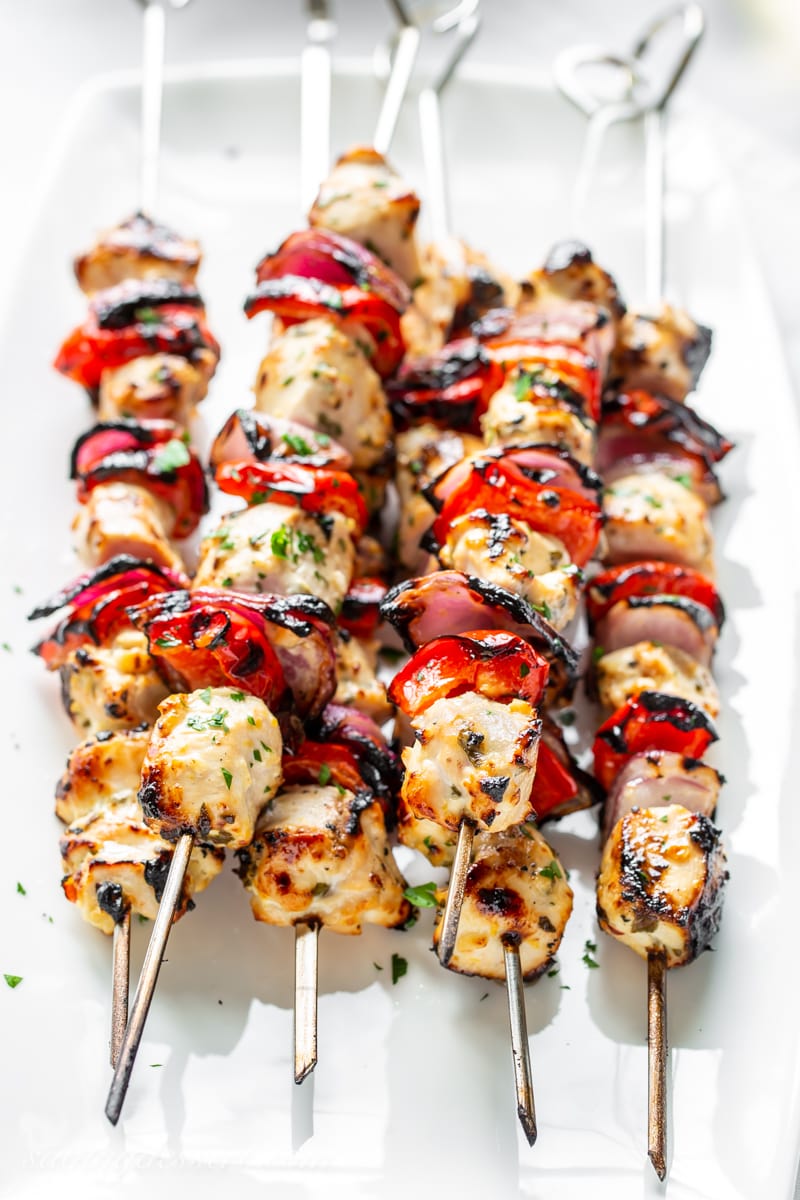 Skewers of Greek flavored chicken pieces on a skewer with red onion and peppers