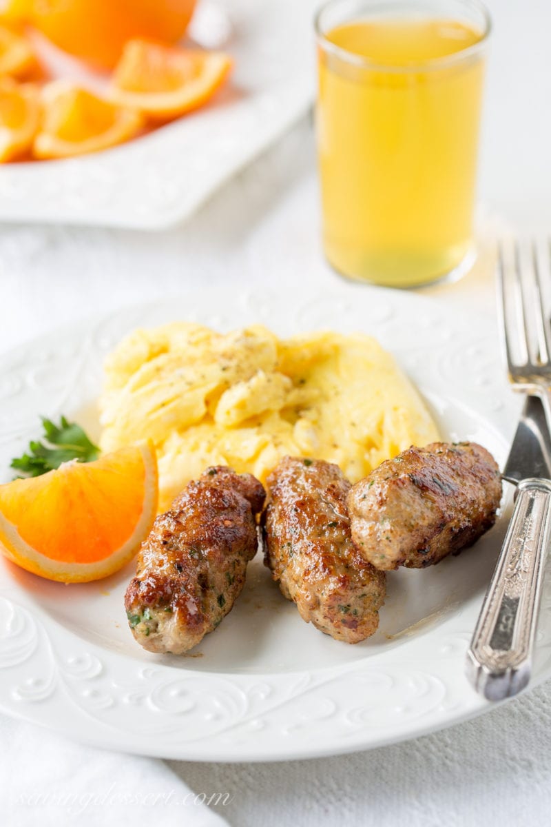 A plate with homemade breakfast sausages, scrambled eggs and oranges