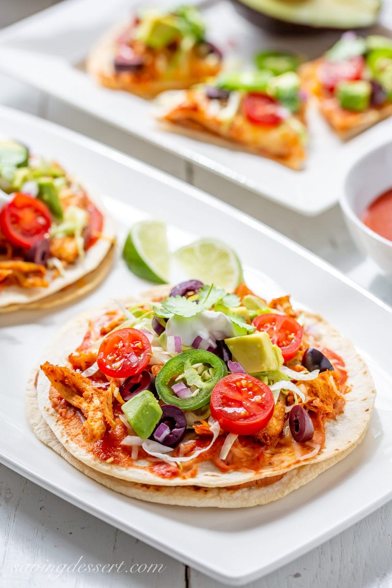 Double decker Mexican Pizzas topped with tomatoes, jalapeños, avocado and lettuce