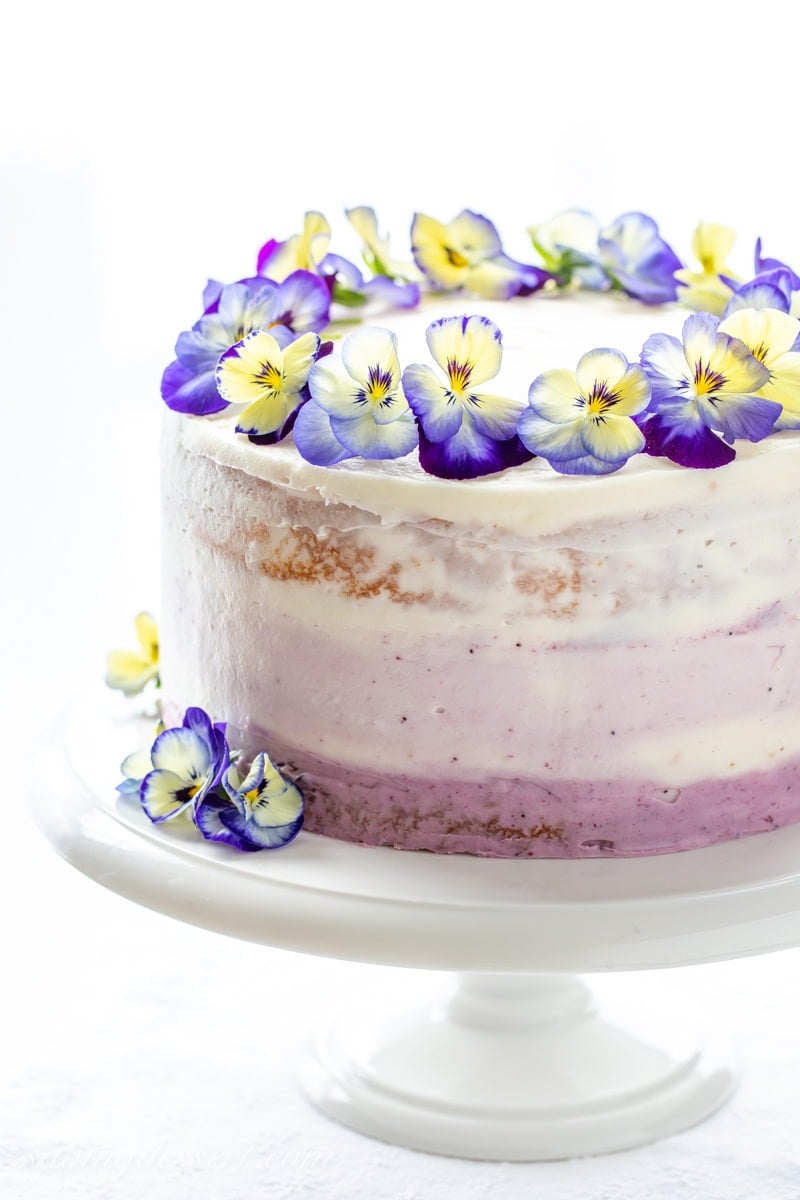 A three layer lemon cake with blueberry filling topped with edible blue and yellow pansies