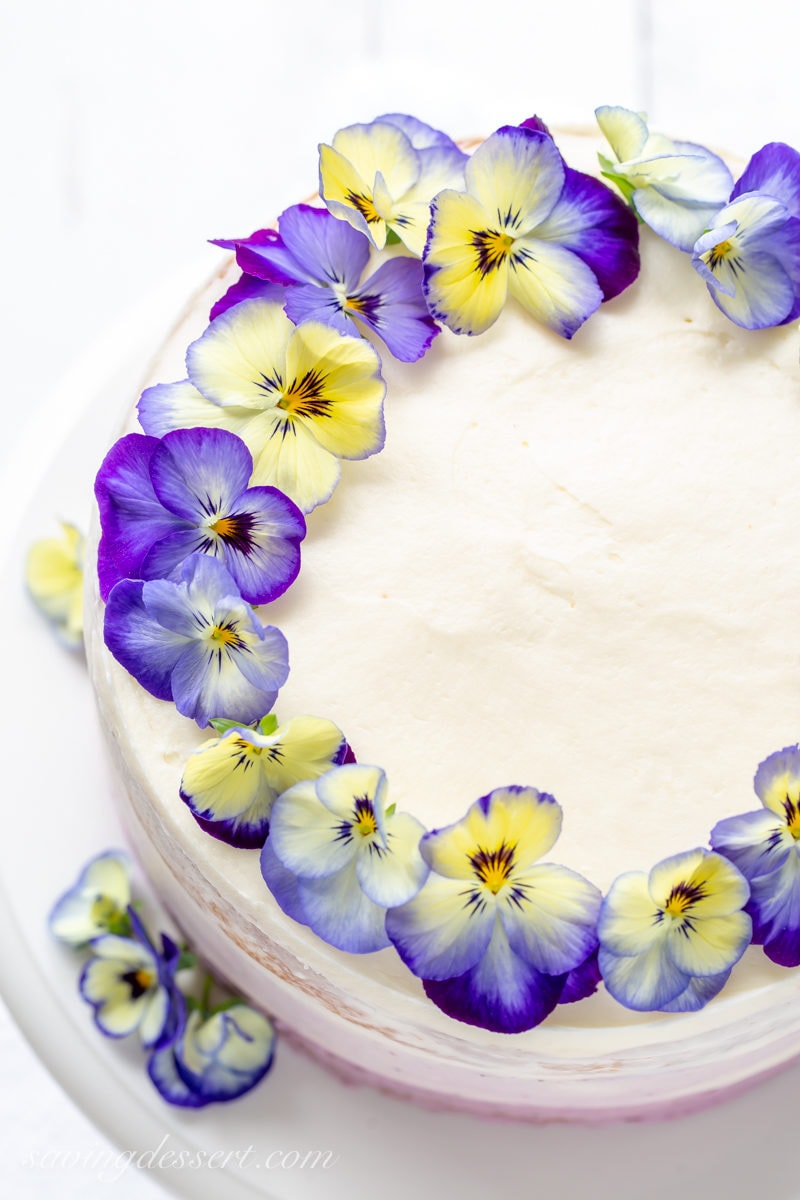 An overhead view of a pretty three layer cake decorated with blue and yellow pansies