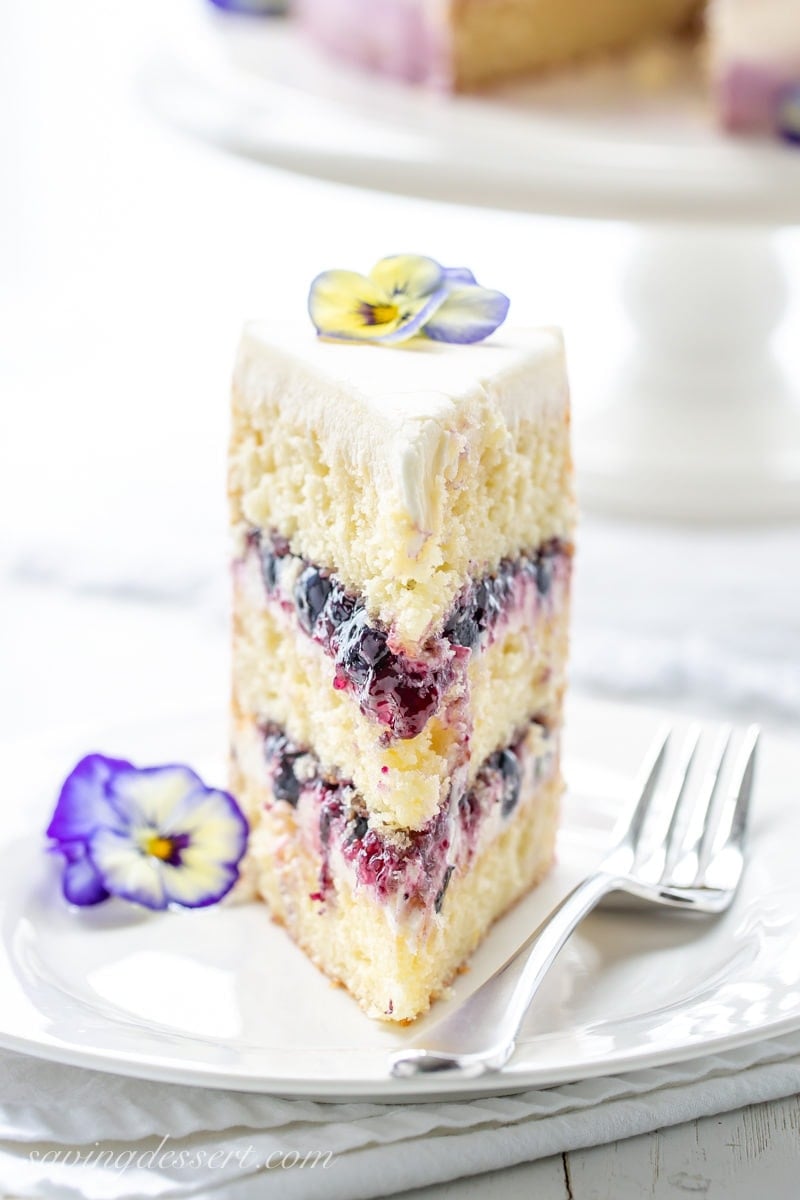 A tall slice of a three layer lemon cake with blueberry filling