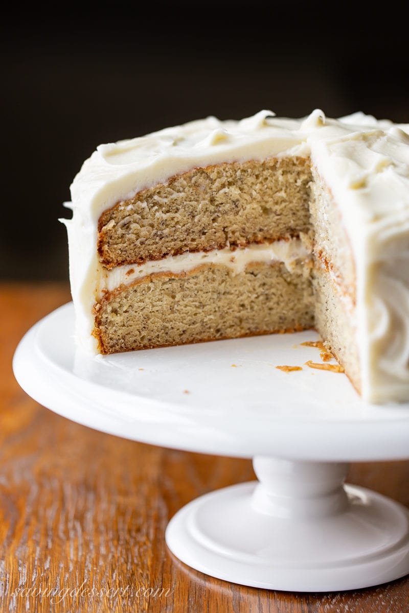 Two layer banana cake on a cake stand with cream cheese frosting