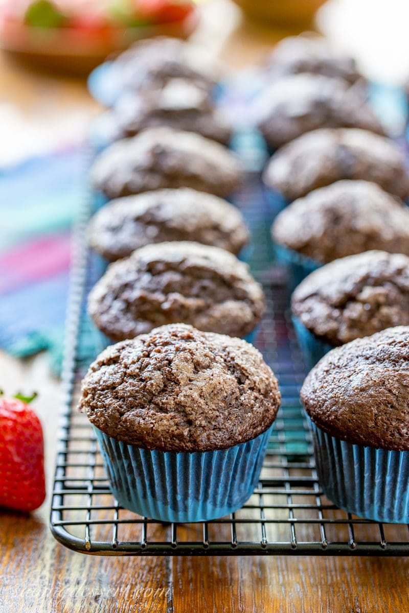 A baking rack filled with dark chocolate muffins topped with coarse sugar