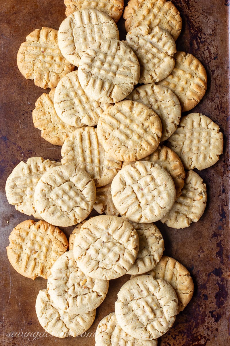A cookie sheet filled with peanut butter cookies with a criss-cross design