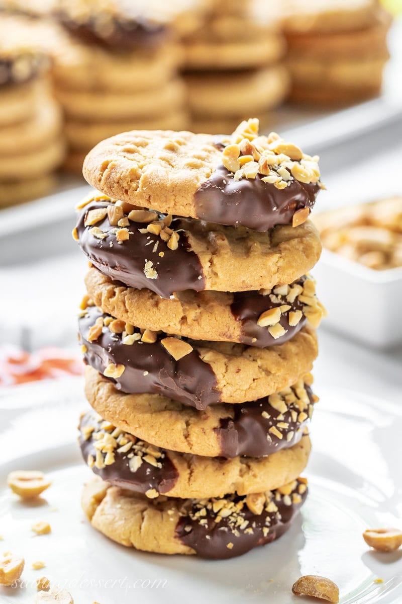 A stack of chocolate dipped peanut butter cookies with chopped peanuts