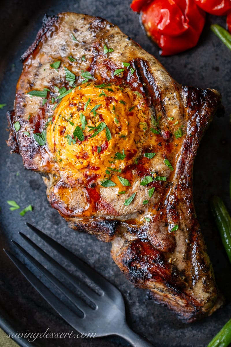 An overhead view of a grilled pork chop topped with chipotle butter and fresh parsley