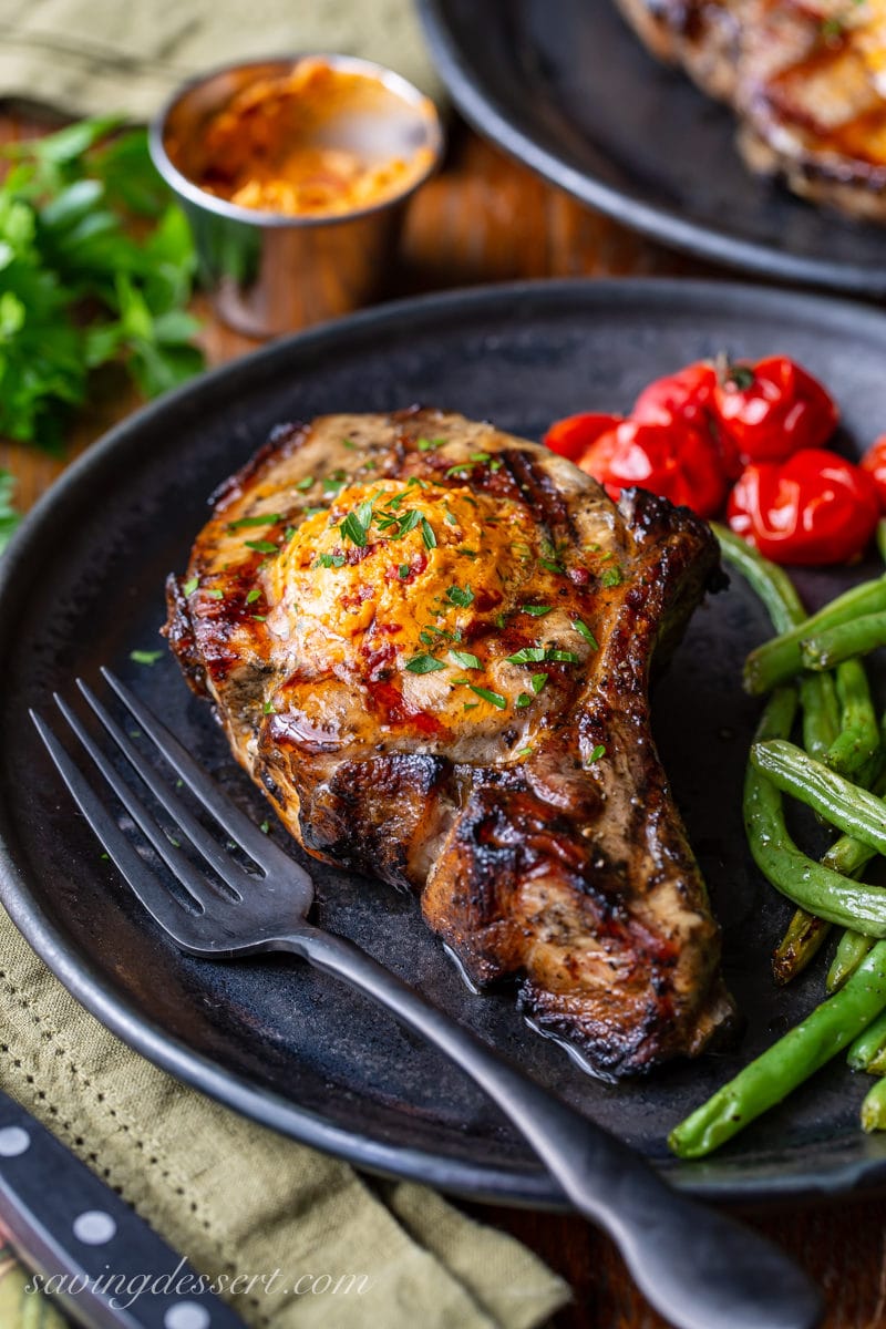 A thick cut grilled pork chop topped with chipotle butter served with green beans and roasted tomatoes