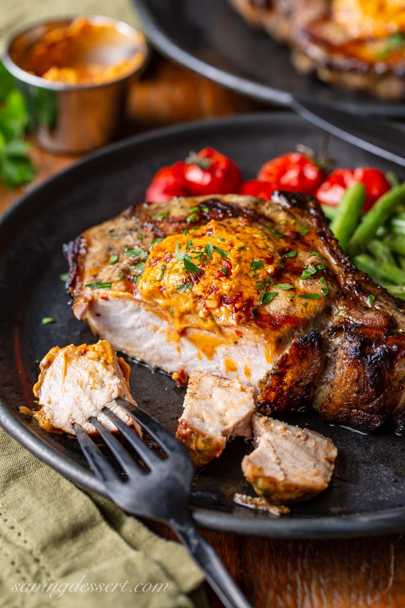 A sliced grilled pork chop topped with chipotle butter and fresh parsley