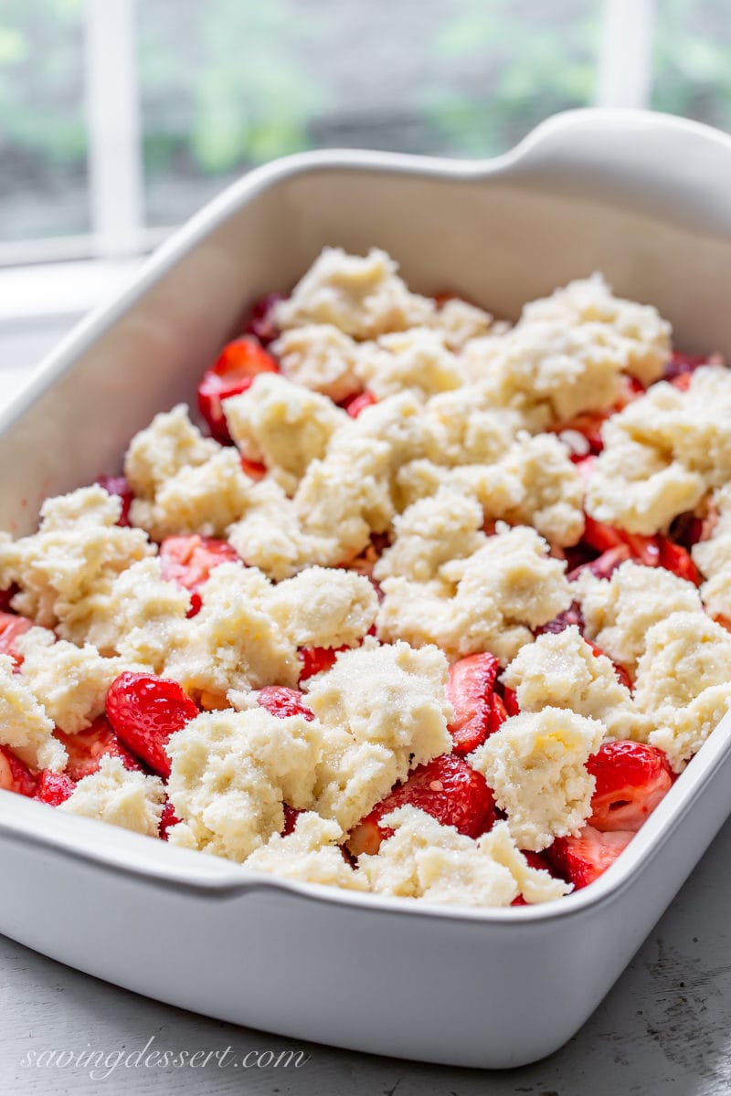 Strawberry cobbler ready to go in the oven with a crumbled biscuit topping